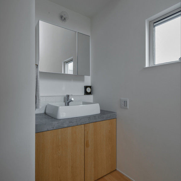 白い陶器の洗面ボウルとホワイトオークの扉が爽やかな洗面スペースの雰囲気を作っています。